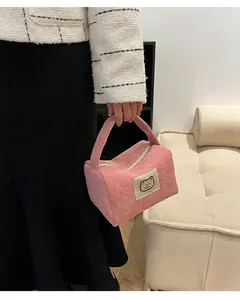 Dettaglio della borsa da trucco in velluto rosa con toppa a orsetto e trama morbida