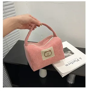 Dettaglio della trousse in velluto rosa con toppa a forma di orso e maniglia