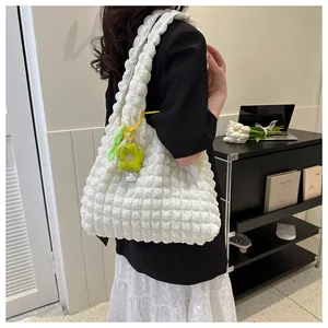 White popcorn textured tote bag with green flower charm worn with a stylish outfit