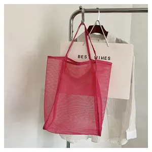 Gros plan sur la maille rose rouge et les doubles poignées d'un sac de plage léger