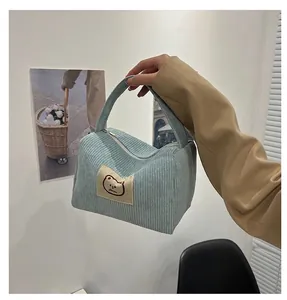 Dettaglio della borsa cosmetica in velluto a coste azzurro con etichetta di un orsetto