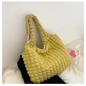 Detail of light yellow bubble fabric shoulder bag with textured surface and soft lining