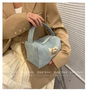 Dettaglio della borsa da trucco in velluto a coste azzurro con toppa a forma di orsetto