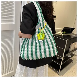 Detail of green and white striped bubble fabric tote bag with a floral charm