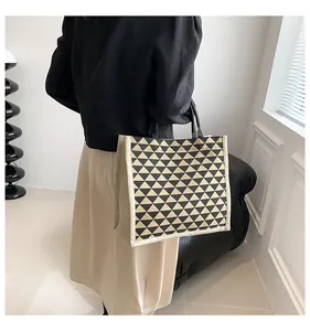 Detail view of canvas tote bag showing black geometric triangles and fabric texture