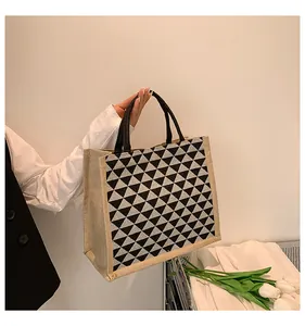Detailed close-up of a jute tote bag with geometric pattern and black woven handles