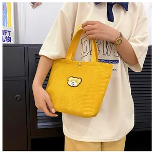 Gele corduroy mini tote bag met berenborduurwerk en drukknoopsluiting in detailweergave