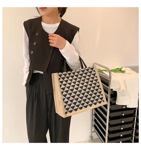 Detail of linen tote bag featuring geometric triangle patterns and sturdy black handles
