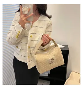Dettaglio della borsa in velluto a coste bianco crema con toppa a orsetto e texture