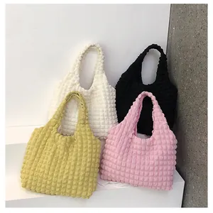 Detail view of colorful bubble textured tote bags in cream black yellow and pink
