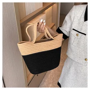Detail of hand-woven two-tone tote bag in beige and black with dual shoulder handles