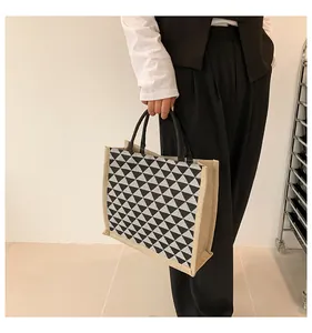 Detailed view of tote bag featuring black geometric triangles and sturdy round handles