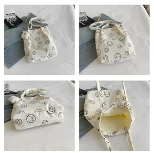 Detail view of white corduroy tote bag with smiley patterns and a plush bear pendant