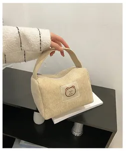 Dettaglio della borsa da toilette in velluto beige con texture morbida e logo a orsetto