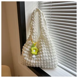 Detail of white popcorn textured tote bag with a small yellow flower charm