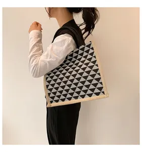 Detail of geometric triangle pattern tote bag with beige woven edges and black wide straps