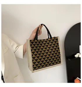 Detail of linen tote bag with geometric triangle patterns and black round handles