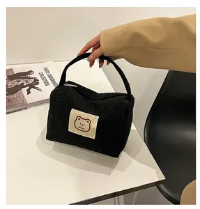 Dettaglio borsa cosmetica in velluto a coste nero con toppa a forma di orso