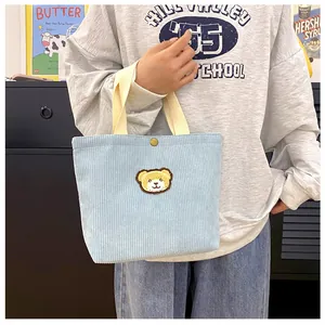 Detail van een lichtblauwe corduroy mini tote bag met schattig geel beertje borduursel