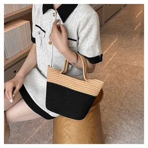 Detail of handwoven straw tote bag in khaki and black color blocking with soft handles