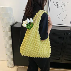 Light yellow puffer tote bag with bubble texture shown on a shoulder in a modern room