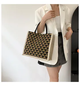 Detail of linen tote bag featuring yellow and black geometric patterns on model