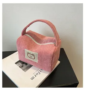 Dettaglio della borsa trucco in velluto rosa con toppa a orsetto e cerniera