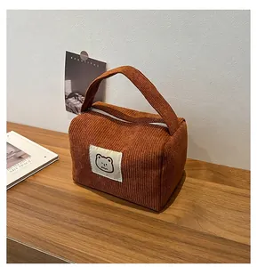 Dettaglio della borsa da toilette in velluto a coste caramello con toppa a forma di orso
