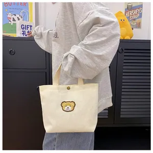 Detail van crème corduroy mini draagtas met schattig teddybeer borduursel en drukknoop