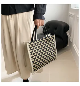 Detail of large tote bag featuring black and beige geometric triangle patterns and handles