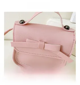 Close-up of pink leather girls crossbody bag with bow decoration and metal snap button