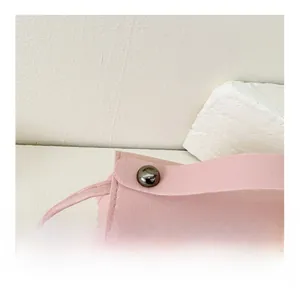 Close-up of pink leather crossbody bag showing fine stitching and metal rivet detail