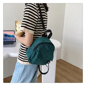 Detalle de mini mochila de pana verde oscuro con textura y bolsillo frontal con solapa
