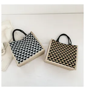 Detail of jute tote bags with geometric triangle prints and round black handles