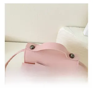 Detailed close-up of a pink mini crossbody bag featuring a leather bow and metal rivets