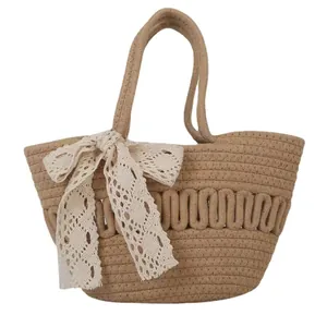 Handwoven straw tote bag with cream lace ribbon bow detail on white background