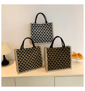Detailed texture of geometric linen tote bags with modern triangular patterns and black handles