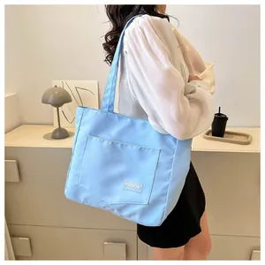 Detail of light blue canvas tote bag featuring an outer pocket and white Fashion label