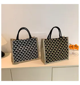 Detail view of geometric triangle pattern jute tote bags with black circular handles