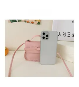 Pink mini crossbody bag with bow detail shown next to a smartphone for size comparison