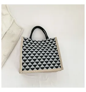 Close-up of geometric pattern linen tote bag with black handles and triangular prints