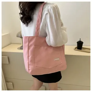 Detailed side view of a pink nylon tote bag with front pocket and fashion label