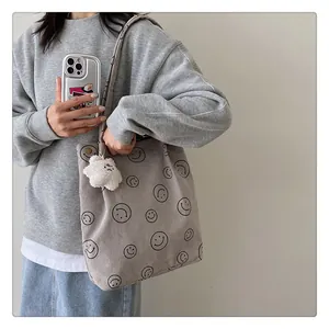 Detail of corduroy tote bag with smiley print and star plush charm on female model