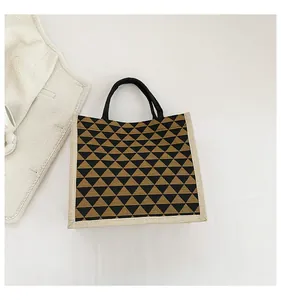 Detail of linen tote bag featuring geometric triangle patterns and sturdy black handles
