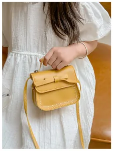 Detailed view of yellow mini crossbody bag for girls with bow and white contrast stitching