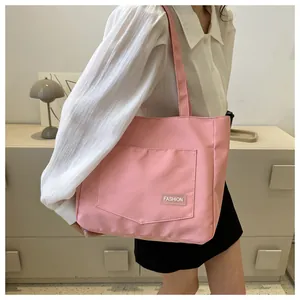 Detail of pink canvas tote bag showing the front pocket with Fashion label and double straps