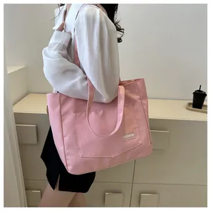 Detailed shot of pink canvas tote bag with front pocket and white fashion label tag