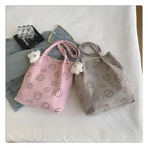Detail of pink and gray corduroy tote bags with smile patterns and plush cloud charms