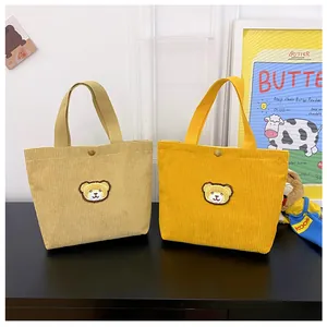 Detailweergave van de kaki en gele corduroy minitassen met schattige teddybeer-patches