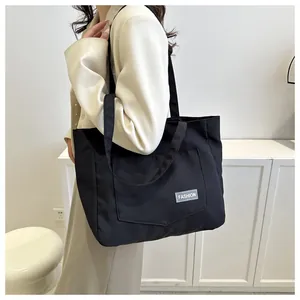 Close-up of black canvas tote bag with functional front pocket and fashion woven label